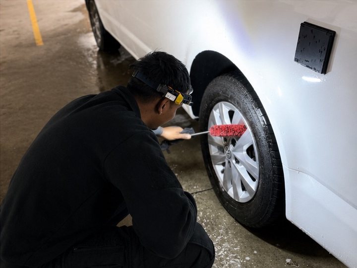 Eine Felge wird mit einer schmalen Detailbürste von Hand gereinigt